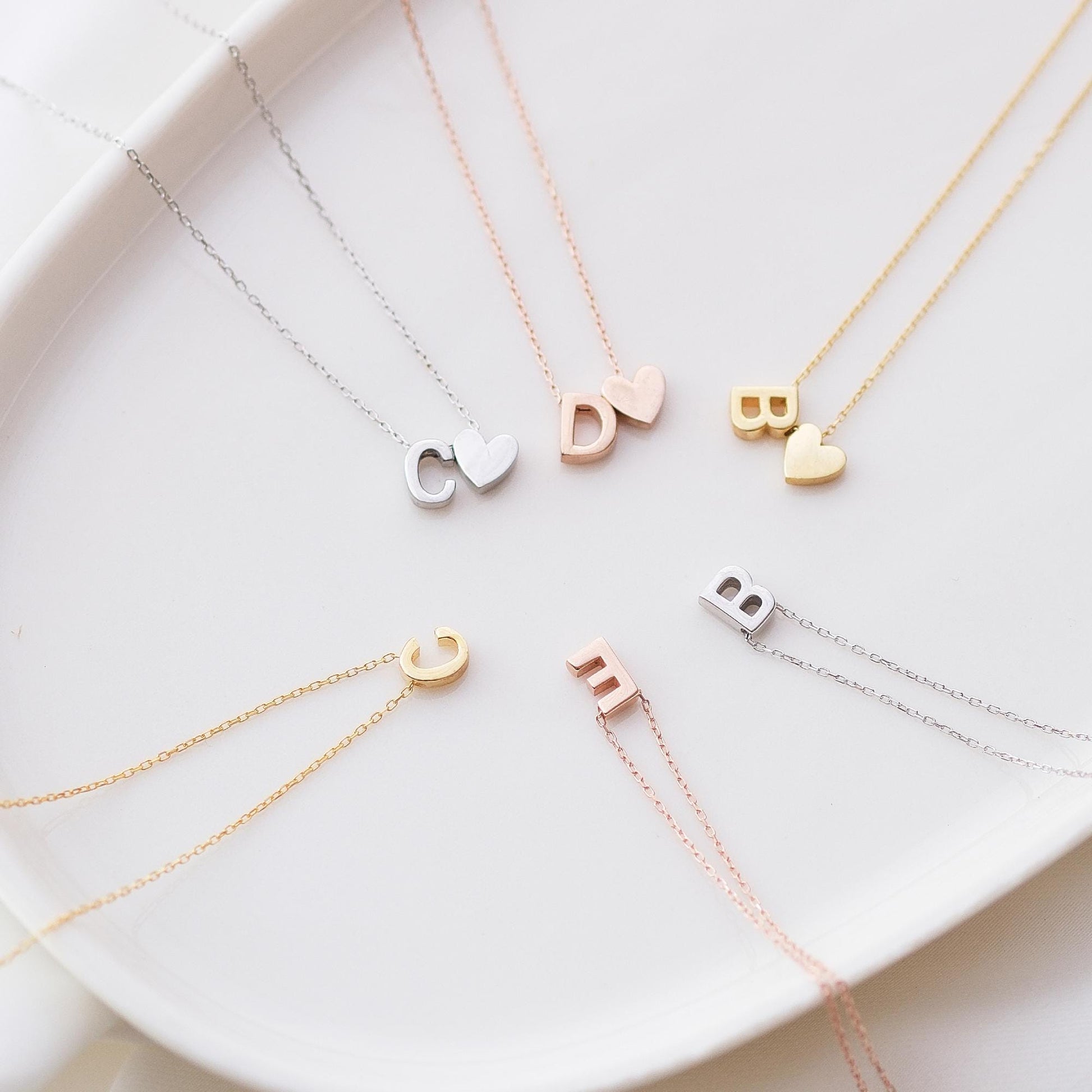 Make a bold statement with our Block Letters Necklace, featuring a heart for a touch of love. Personalize it with your name or a meaningful word. Available in gold, silver, and rose gold this piece adds a modern stylish and personal touch to any look