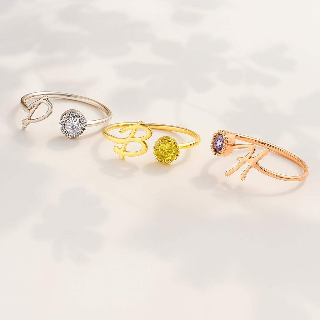 Sterling silver and gold personalized initial rings with sparkling birthstones, shown in D, B, and K letters in different finishes.